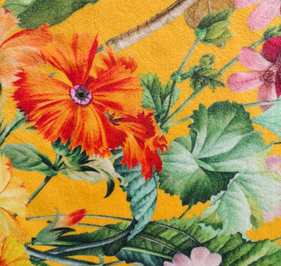 close up of meadow velvet lampshade in sunshine yellow, showing the bright yellow background, colourful flowers and green leaves