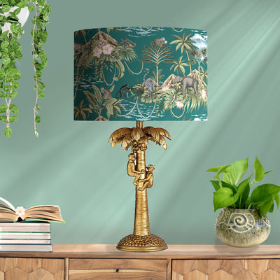 Green Lemur Island Cotton Lampshade with Mirror Copper Lining, pictured in living room setting on a gold monkey lamp base
