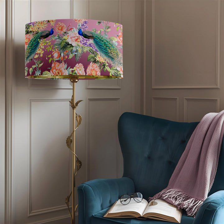 Peacock Paradise velvet lampshade displayed on a gold floor lamp beside a teal armchair in a cosy reading corner.