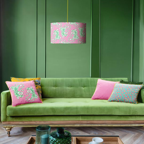 Candy pink tiger roar lampshade hanging in green living room with green sofa and matching tiger roar cushion 